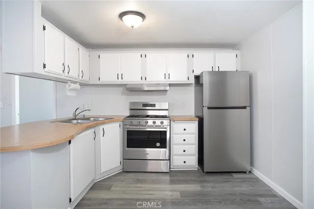 a kitchen with stainless steel appliances granite countertop a refrigerator stove a sink and white cabinets