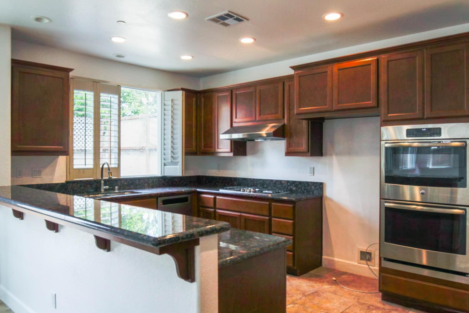 1817 Thomas Court Modesto, CA 95355 - Photo 5 of 20 a kitchen with kitchen island granite countertop a sink window and cabinets