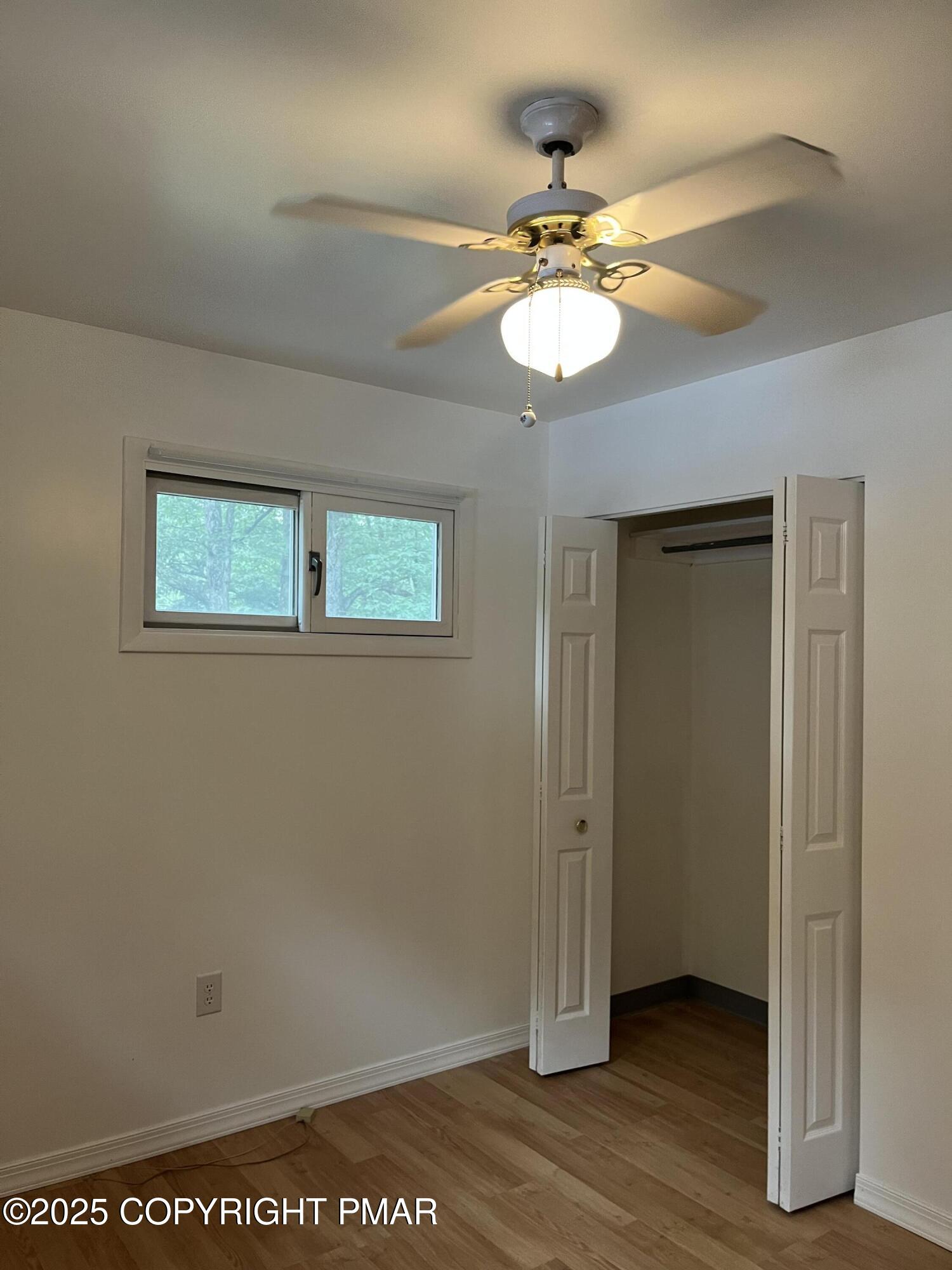 529 Pine Ridge Road Stroudsburg, PA 18360 - Photo 29 of 36 an empty room with wooden floor chandelier fan and windows