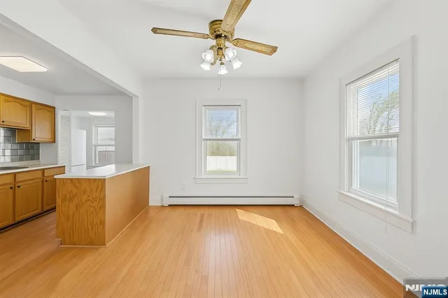 a large white kitchen with wooden floor and a window