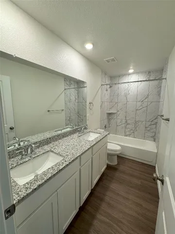 a bathroom with a granite countertop sink a toilet and bathtub