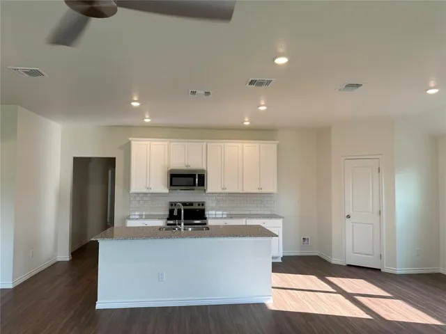a living room with stainless steel appliances kitchen island granite countertop a refrigerator and a stove top oven