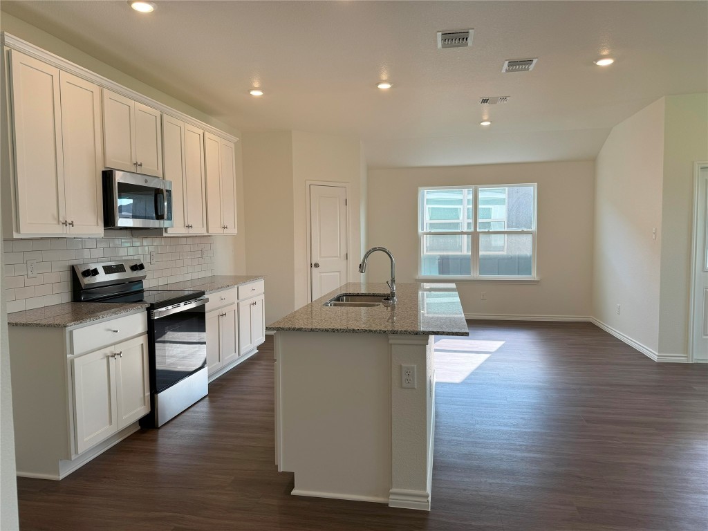 501 Double Vision Road Jarrell, TX 76537 - Photo 6 of 36 a kitchen with stainless steel appliances granite countertop a stove a sink and a microwave