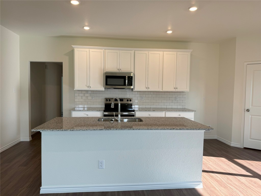 501 Double Vision Road Jarrell, TX 76537 - Photo 7 of 36 a kitchen with kitchen island granite countertop a sink a stove a refrigerator a microwave and cabinets