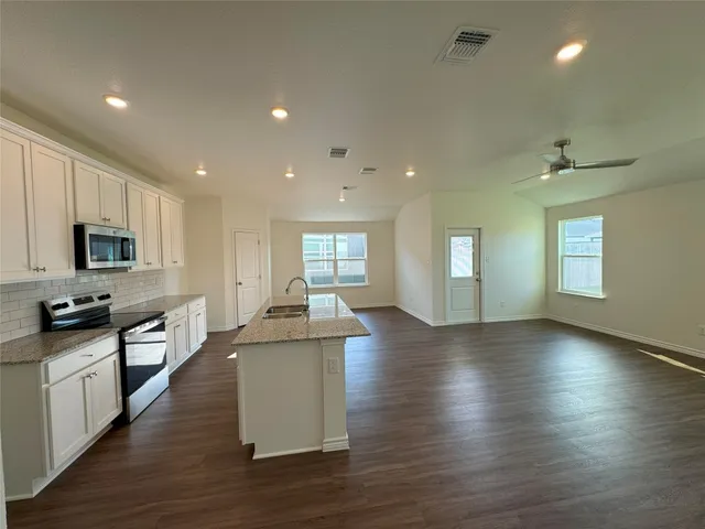 a kitchen with stainless steel appliances granite countertop a sink stove and wooden floor