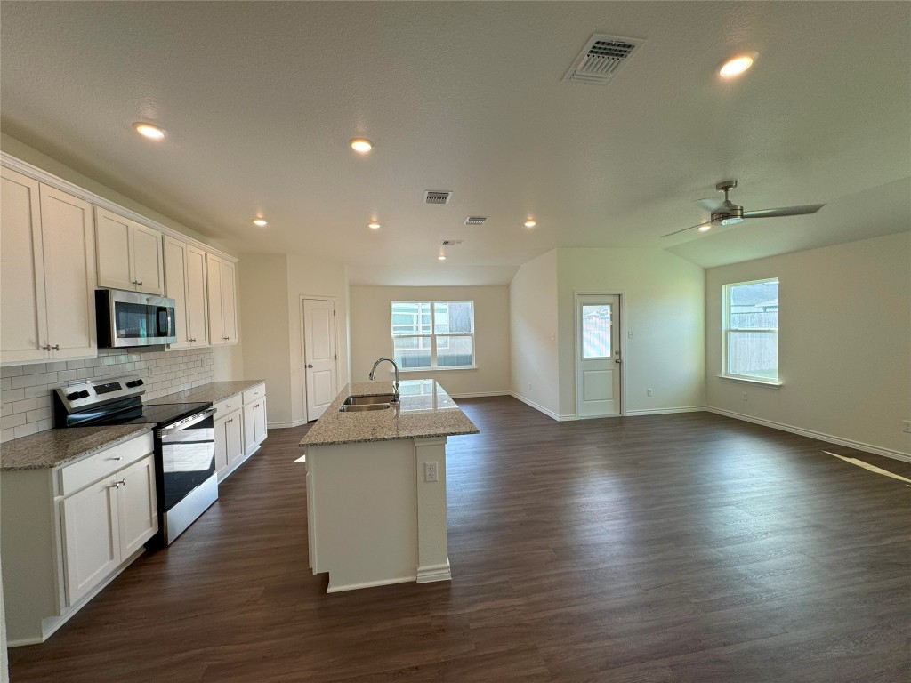 501 Double Vision Road Jarrell, TX 76537 - Photo 10 of 36 a kitchen with stainless steel appliances granite countertop a sink stove and wooden floor