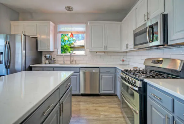 a kitchen with kitchen island granite countertop a sink cabinets stainless steel appliances and a counter space