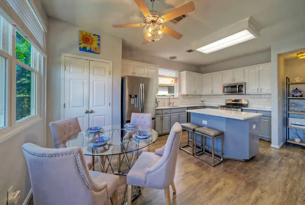 a kitchen with stainless steel appliances granite countertop a refrigerator a stove top oven a dining table and chairs with wooden floor