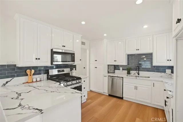 a kitchen with stainless steel appliances a sink a stove a microwave a center island and cabinets