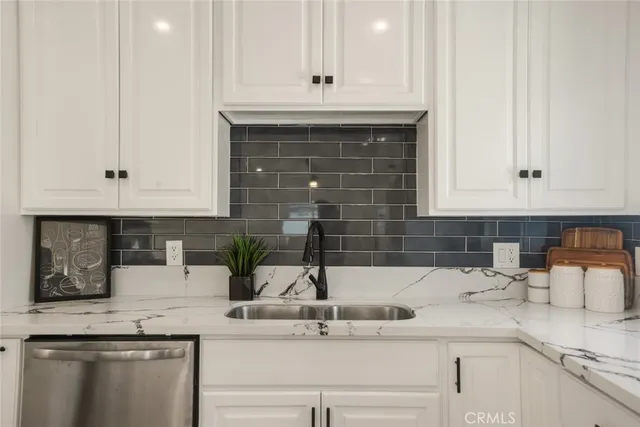 a kitchen with granite countertop white cabinets and a sink