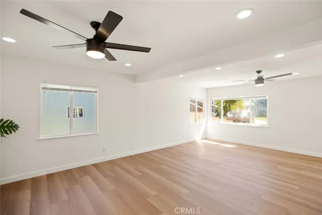 a view of an empty room with window and wooden floor