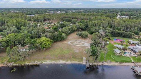 an aerial view of a houses with a yard and lake