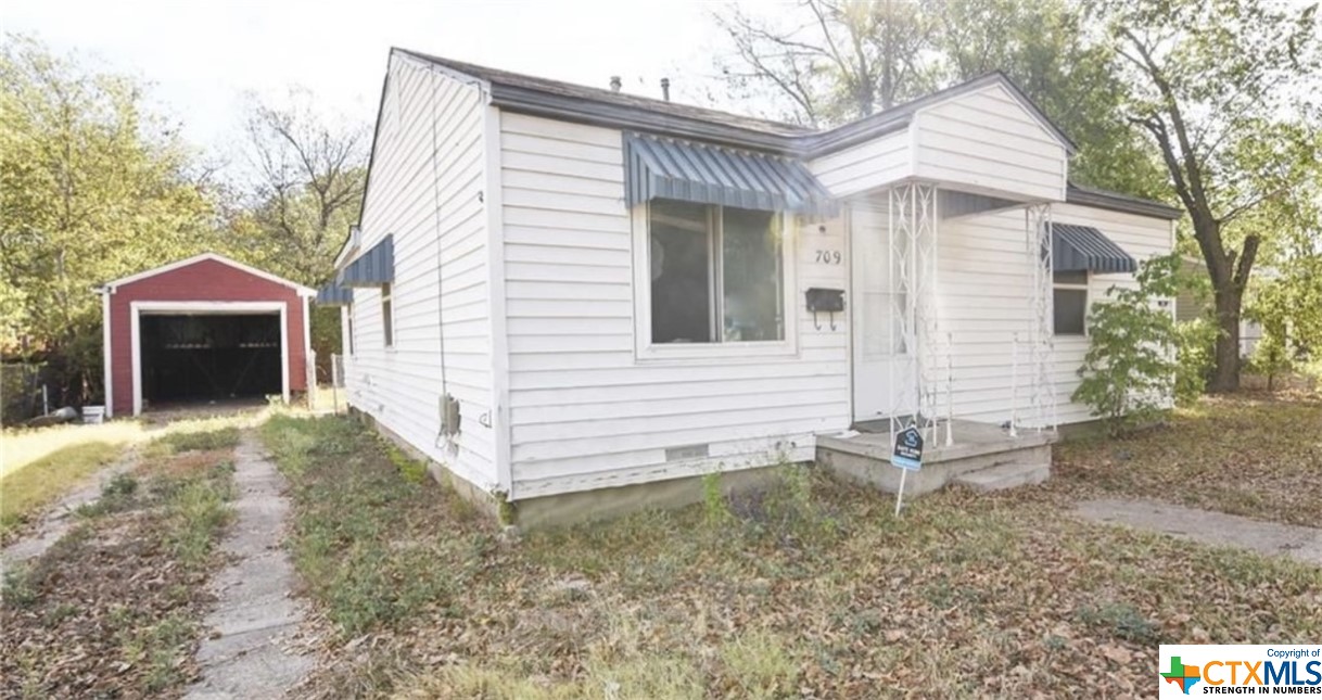 a view of a house with a yard and a large tree