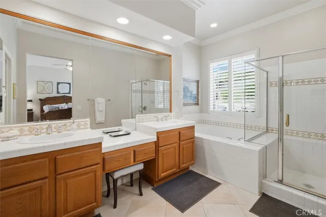 a bathroom with a sink double vanity granite tub shower and mirror