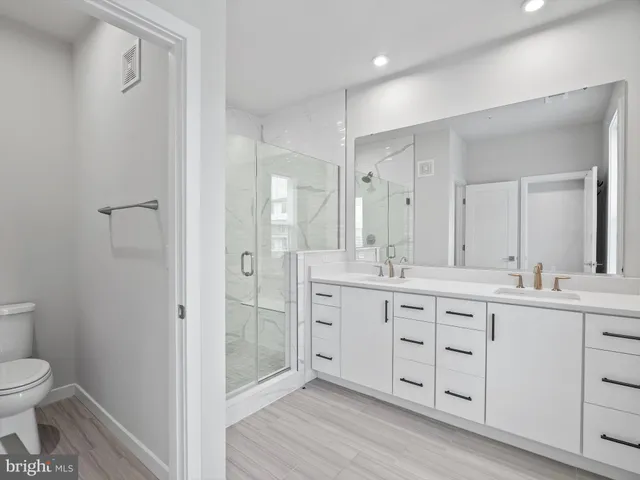 a spacious bathroom with a double vanity sink a toilet and a shower