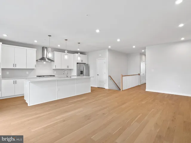 a large white kitchen with kitchen island a sink a center island stainless steel appliances and a cabinets