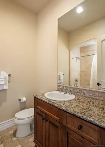 a bathroom with a granite countertop sink a toilet and a mirror
