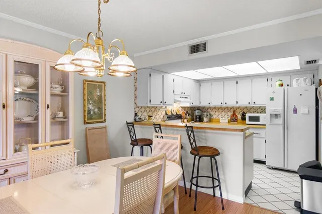 a kitchen with stainless steel appliances a dining table chairs and white cabinets