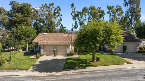 a view of a white house with a tree and plants