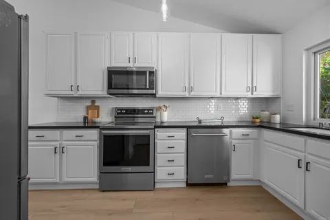 a kitchen with granite countertop white cabinets and stainless steel appliances