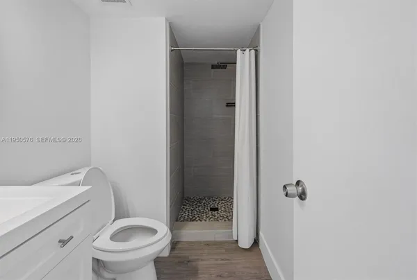 a bathroom with a granite countertop toilet a sink and shower