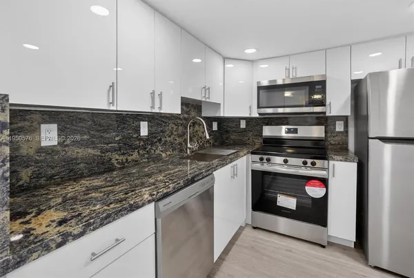 a kitchen with stainless steel appliances granite countertop a stove a refrigerator and a microwave