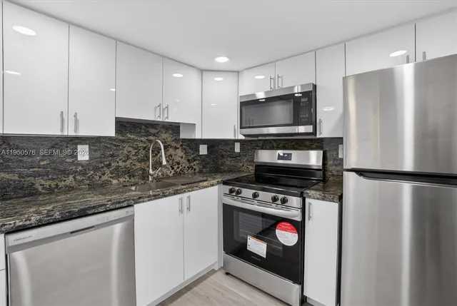 a kitchen with granite countertop a refrigerator a stove a sink and a microwave