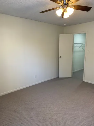 an empty room with a fan and a chandelier fan