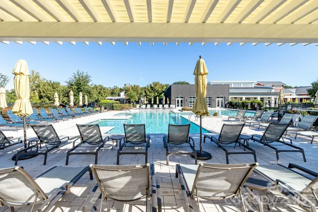 a view of a swimming pool with lawn chairs under an umbrella