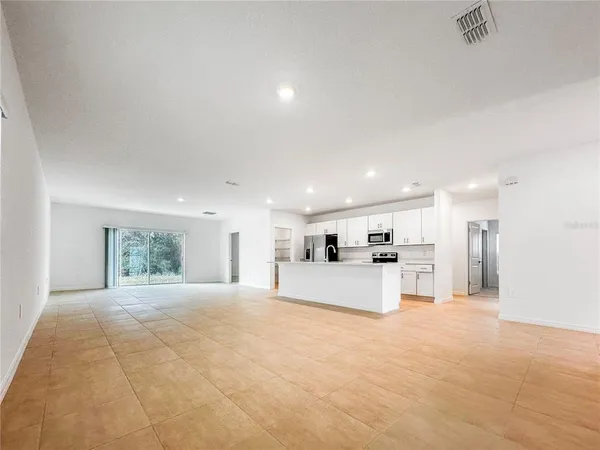 a large white kitchen with kitchen island a stove a refrigerator with white cabinets and large windows