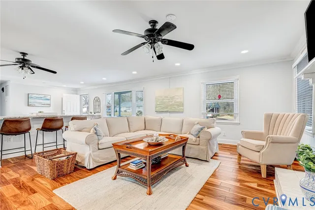 a living room with furniture kitchen view and a wooden floor