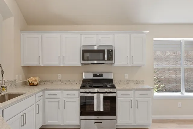 a kitchen with white cabinets and appliances