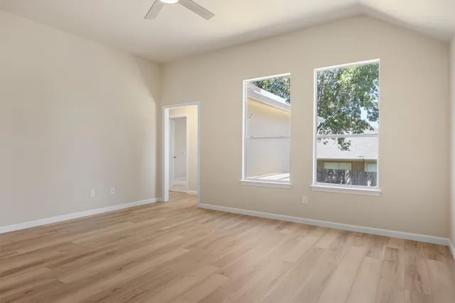 a view of an empty room with a window and wooden floor