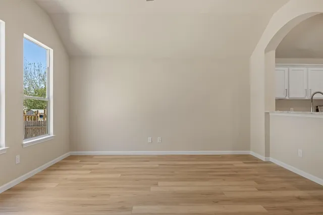 a view of an empty room with window and wooden floor