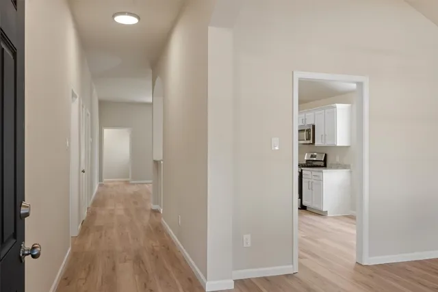 a view of a hallway with wooden floor and a bathroom
