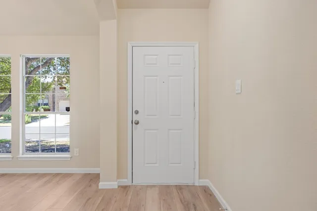 a view of an empty room with wooden floor and a window