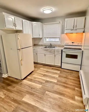 a kitchen with granite countertop white cabinets and white appliances