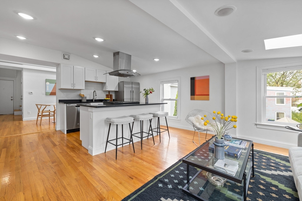 25 Clark Street, Unit 2 Somerville, MA 02143 - Photo 3 of 20 a kitchen with stainless steel appliances granite countertop a stove top oven a sink a dining table and chairs with wooden floor