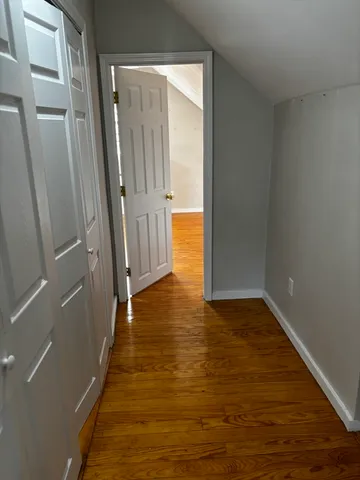 a view of a hallway with wooden floor and a bathroom