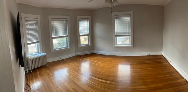 an empty room with wooden floor and windows