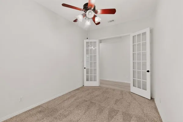 an empty room with windows and fan