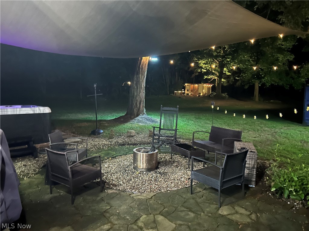 4824 Manchester Road Akron, OH 44319 - Photo 33 of 39 Stone patio featuring a central gravel fire pit area with a permanent fire pit, an overhead shade sail, string lights, and a hot tub