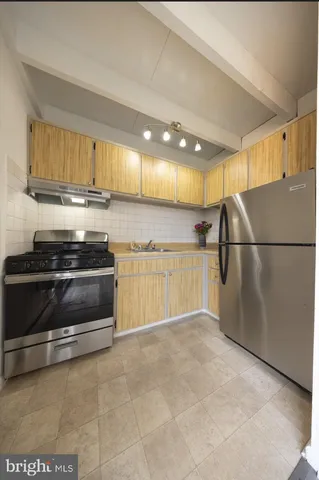 a view of kitchen with stainless steel appliances wooden floor and window