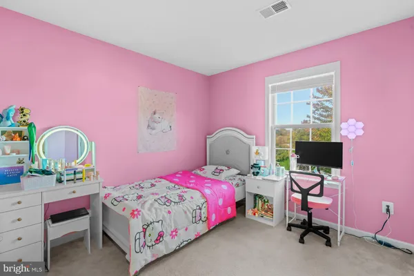 a bedroom with a bed table chair and a window