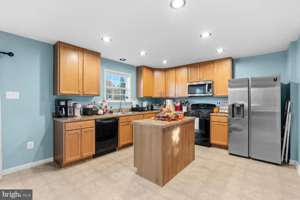 a kitchen with stainless steel appliances granite countertop a stove top oven a refrigerator a sink and dishwasher