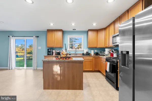 a kitchen with stainless steel appliances granite countertop a refrigerator a sink a stove and a refrigerator
