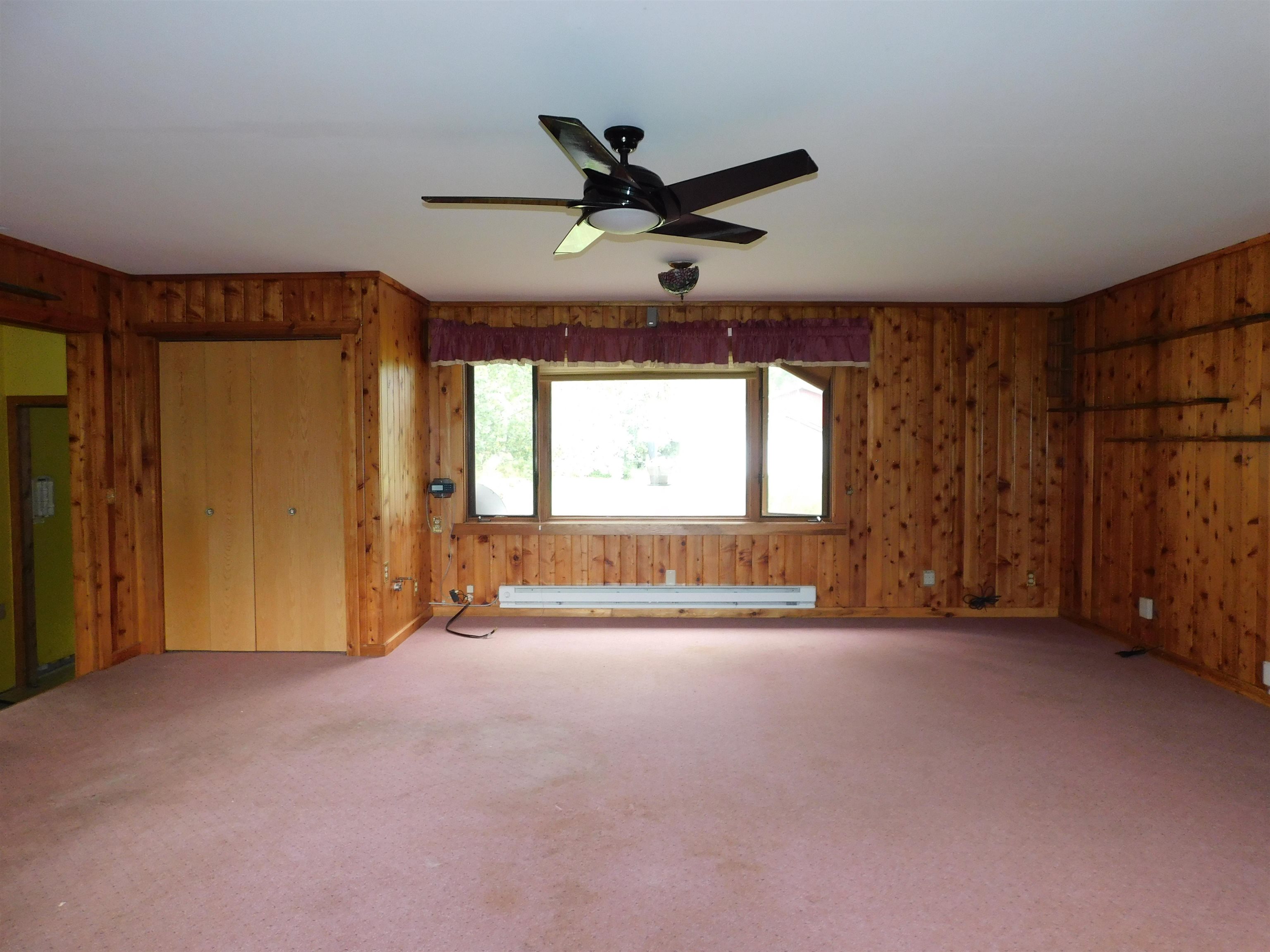 4036 County Rd A Superior, WI 54880 - Photo 12 of 52 Carpeted spare room featuring a baseboard radiator, ceiling fan, and wood walls