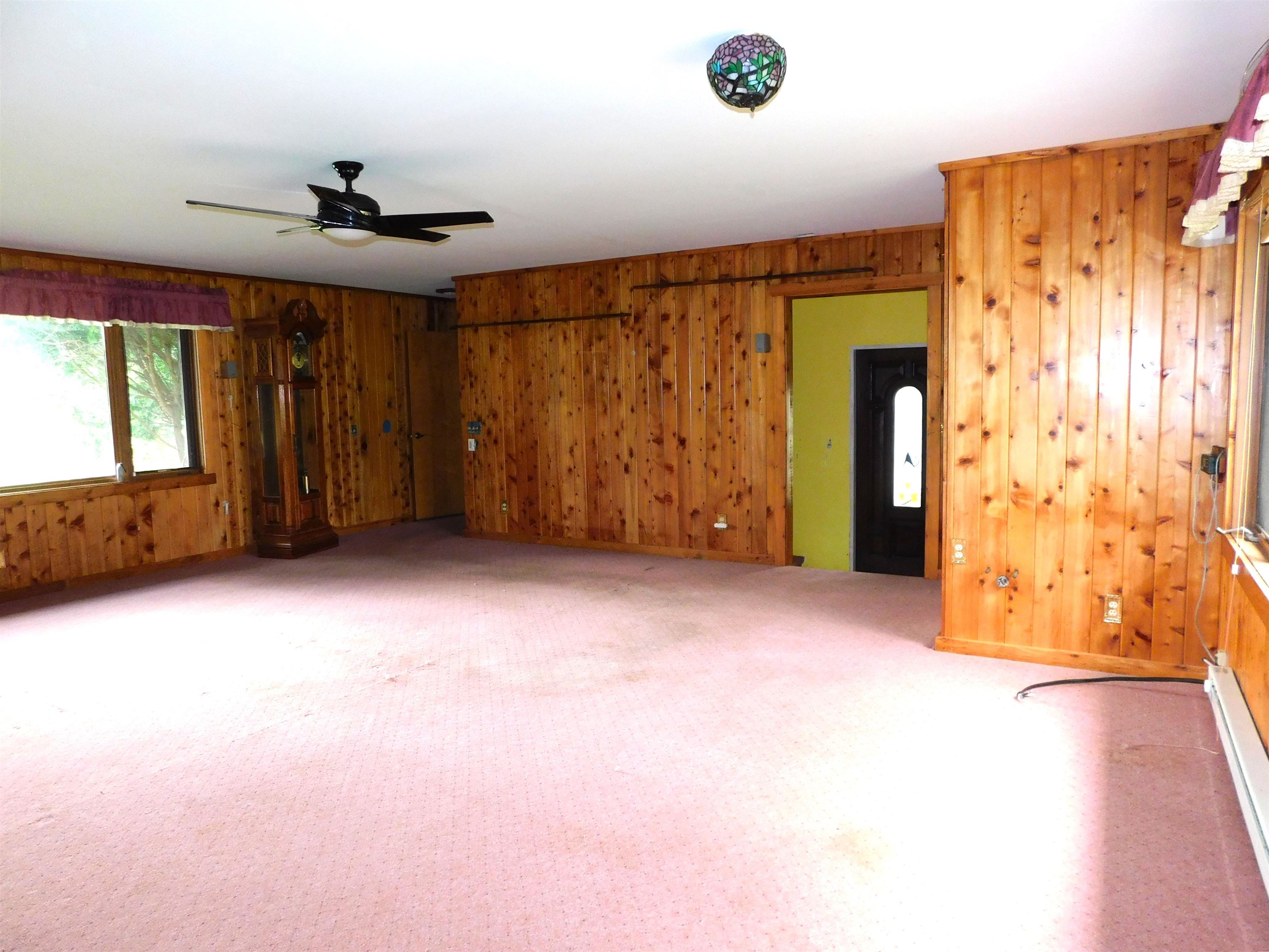 4036 County Rd A Superior, WI 54880 - Photo 14 of 52 Unfurnished room with wooden walls, a ceiling fan, a baseboard heating unit, and light carpet
