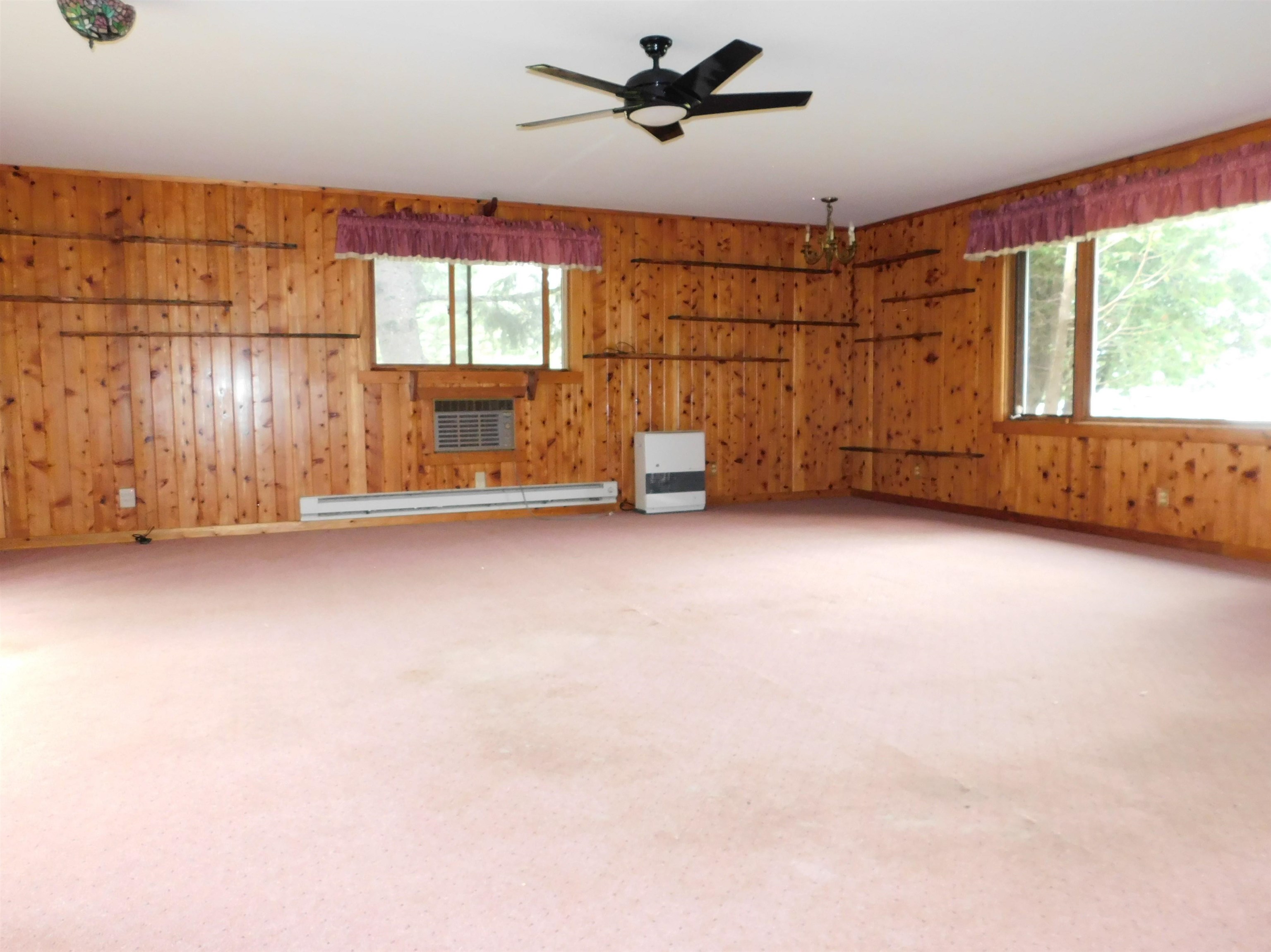 4036 County Rd A Superior, WI 54880 - Photo 15 of 52 Spare room featuring wood walls, plenty of natural light, a baseboard radiator, a ceiling fan, and a wall mounted AC