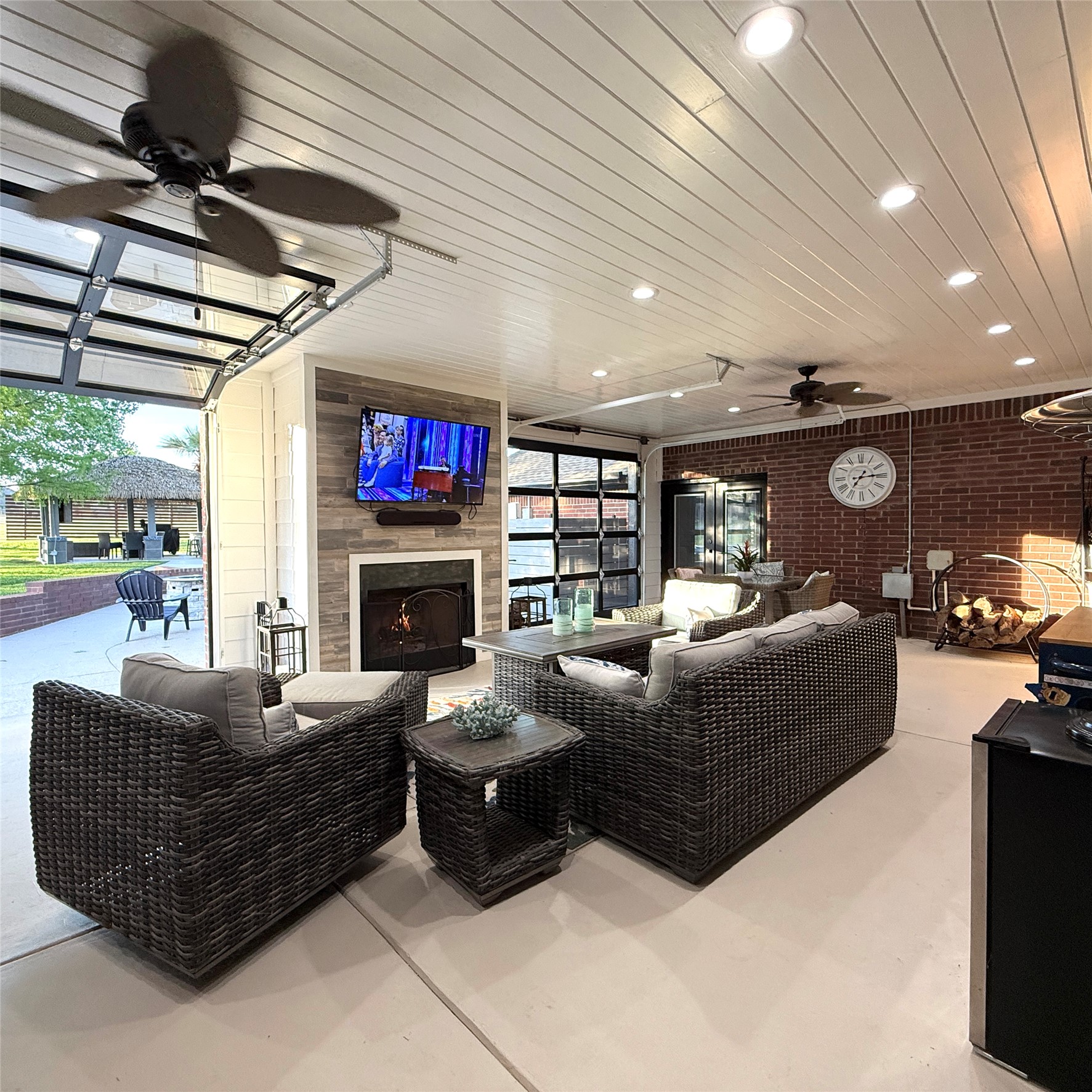 1902 Rowe Loop Pflugerville, TX 78660 - Photo 7 of 38 Outdoor living area with ceiling fan, concrete floors, a warm lit fireplace, brick wall, and wood ceiling. Heated and cooled.